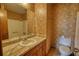 Cozy bathroom with marble countertop, wood cabinets, and floral wallpaper at 2140 Teri Ln, Conyers, GA 30013