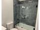 Contemporary bathroom featuring toilet and glass shower/tub combo with dark stone tile surround at 437 Collier Ridge Nw Dr, Atlanta, GA 30318