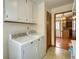 Functional laundry room features a washer, dryer, overhead cabinet storage, and tile flooring at 4814 Riveredge Cv, Snellville, GA 30039