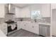 Well-lit kitchen features white cabinets, stainless steel appliances, quartz countertops, and a modern faucet at 5469 Helen Pl Sw, Mableton, GA 30126