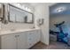 Well-lit bathroom with double vanity, large mirror, and a glimpse into adjacent exercise room at 7415 Northampton Ct, Cumming, GA 30040