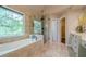 Well-appointed bathroom showcasing a soaking tub, glass enclosed shower, and decorative window at 7415 Northampton Ct, Cumming, GA 30040