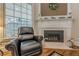 Cozy living room with fireplace, leather recliner, and large windows with views of the home's natural surroundings at 7415 Northampton Ct, Cumming, GA 30040