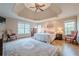 Spacious primary bedroom with a trey ceiling, hardwood floors, large windows, and comfortable furnishings at 7415 Northampton Ct, Cumming, GA 30040