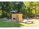 Community playground featuring climbing structure, slides, and benches in a wooded setting at 7415 Northampton Ct, Cumming, GA 30040