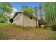 Rear view of a brick home with a wooden deck, surrounded by mature trees and greenery at 4595 Fradon Ct, Atlanta, GA 30349