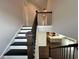 View of the home's staircase flowing to a modern kitchen with stainless appliances and island seating at 5458 Summer Pine Pl, Buford, GA 30518