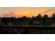 A beautiful sunset view from the deck overlooking a neighborhood with green spaces and trees at 5458 Summer Pine Pl, Buford, GA 30518