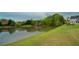 Scenic view of a community pond surrounded by lush green grass and mature trees at 2557 Staunton Dr, Duluth, GA 30097