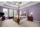 Main bedroom featuring a tray ceiling, four-poster bed, a ceiling fan, and carpeted floors at 5628 Harbormist Dr, Powder Springs, GA 30127