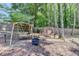 Charming backyard complete with wooden swing sets, a fire pit, and mature trees creating a relaxing outdoor space at 7020 Grassmoor Grange Way, Cumming, GA 30040