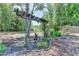 Beautiful backyard featuring landscaped garden area, decorative art, mature trees, and rock ground cover at 7020 Grassmoor Grange Way, Cumming, GA 30040