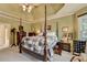 Spacious bedroom with a large four-poster bed, tray ceiling, and a window for natural light at 7020 Grassmoor Grange Way, Cumming, GA 30040