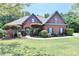 Charming brick home featuring a well-manicured lawn, mature trees, and arched entryway at 7020 Grassmoor Grange Way, Cumming, GA 30040