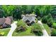Aerial view of brick home with gray roof, circular driveway, and lush landscaping surrounded by mature trees at 7020 Grassmoor Grange Way, Cumming, GA 30040