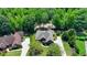 Aerial view of brick home with gray roof, circular driveway, and lush landscaping surrounded by mature trees at 7020 Grassmoor Grange Way, Cumming, GA 30040