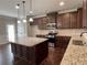 Modern kitchen with granite countertops, island, stainless steel appliances, and dark wood cabinets at 725 Valley Glen Dr, Dacula, GA 30019