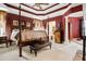 Luxurious main bedroom with four-poster bed, tray ceiling, and sitting area at 3902 Butterstream Nw Way, Kennesaw, GA 30144