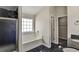 Elegant bathroom with a soaking tub, glass-enclosed shower, and black tile flooring at 6793 Oconee Pl, Fairburn, GA 30213