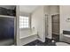 Modern bathroom featuring a tiled shower, a jetted tub under a window, and a dark tiled floor at 6793 Oconee Pl, Fairburn, GA 30213