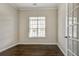 Bright bedroom featuring a window, dark hardwood floors, and a glass door at 6793 Oconee Pl, Fairburn, GA 30213