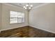 Well-lit dining room featuring hardwood floors, a classic chandelier, and a large window at 6793 Oconee Pl, Fairburn, GA 30213