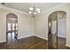 Elegant dining room featuring dark hardwood floors, arched doorways and a decorative chandelier at 6793 Oconee Pl, Fairburn, GA 30213