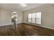 Open living room featuring hardwood floors and large windows with connecting kitchen space at 6793 Oconee Pl, Fairburn, GA 30213