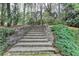 Landscaped backyard featuring stone steps, lush greenery, mature trees, and an inviting outdoor space at 8070 Georgetown Cir, Suwanee, GA 30024