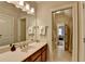 Bathroom featuring a long vanity with dual sinks, a large mirror, and an open doorway to a bedroom at 8070 Georgetown Cir, Suwanee, GA 30024
