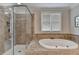 A stunning bathroom features a jetted tub, tiled shower, and natural light from the window at 8070 Georgetown Cir, Suwanee, GA 30024