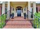 Charming front entrance with brick stairs, black railings, flower planters and large columns at 8070 Georgetown Cir, Suwanee, GA 30024