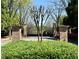View of the gated entry to this lovely property with brick pillars and mature landscaping at 8070 Georgetown Cir, Suwanee, GA 30024