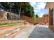 Tiled backyard featuring a brick retaining wall and mature trees at 488 Takely Dr, Lawrenceville, GA 30046