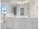 Elegant bathroom featuring a double vanity, decorative mirror, and a stained glass window at 488 Takely Dr, Lawrenceville, GA 30046