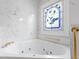 Bathroom featuring a soaking tub with tile surround and a decorative stained glass window at 488 Takely Dr, Lawrenceville, GA 30046