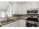 Corner of kitchen featuring stainless steel microwave and stove top with white cabinets and granite countertops at 208 Julia Lynn Ln, Acworth, GA 30102