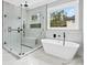 Modern bathroom with glass shower, soaking tub, and marble tile, offering a spa-like experience at 2107 E Maddox Rd, Buford, GA 30519