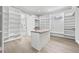 Bright walk-in closet with custom white shelving, central island and natural light at 2107 E Maddox Rd, Buford, GA 30519
