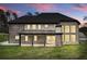 View of back of home, showing covered patio, brick exterior, and expansive windows at sunset at 2107 E Maddox Rd, Buford, GA 30519