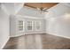Spacious bedroom featuring a tray ceiling, modern ceiling fan, and three large windows at 295 Langshire Dr, Mcdonough, GA 30253