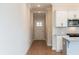 Hallway leading to a modern kitchen featuring white cabinets, stainless appliances, and granite counters at 409 Carrera Ln, Acworth, GA 30102