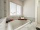 Soaking tub with marble tile surround, tray, reading materials, and spa accessories at 1166 Farmstead Rd, Suwanee, GA 30024
