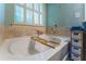 Relaxing primary bathroom soaking tub with tile surround, bath caddy, and bright window light at 2436 Sardis Chase Ct, Buford, GA 30519