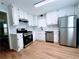 Well-lit kitchen with white cabinets, stainless steel appliances, hardwood floors, and polka dot backsplash at 440 Sheppard Xing Ct, Stone Mountain, GA 30083