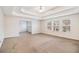Spacious living room featuring tray ceilings, neutral paint and carpet, and large windows at 2036 Broadmoor Way, Fairburn, GA 30213
