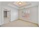 Well-lit bedroom featuring a tray ceiling, shuttered windows, and access to another room at 1662 Hartford Ne Gln, Atlanta, GA 30319