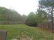 Fenced in backyard with a grassy hill, and multiple mature trees at 1325 Sandlewood Ct, Lithonia, GA 30058