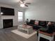 Inviting living room featuring a fireplace, ceiling fan, gray flooring, and cozy leather sofa at 1325 Sandlewood Ct, Lithonia, GA 30058