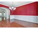 Elegant dining room with hardwood floors, red accent wall, and classic chandelier at 159 Molly Way, Mcdonough, GA 30253